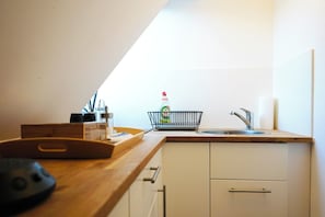 A kitchen with a wooden countertop, a sink, and a dish rack. - green-man Marktplatz Apartments (Wolfsburg)