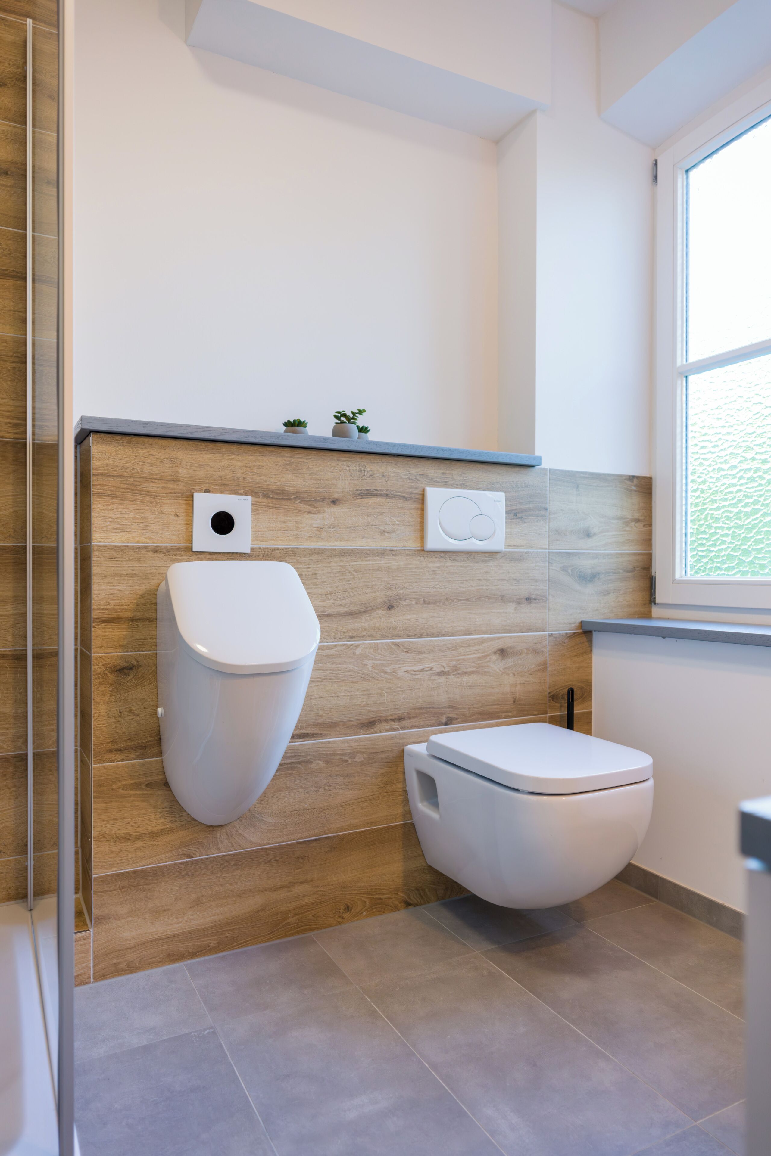 A modern bathroom with a wooden accent wall, a toilet, and a bidet.