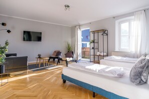 A modern living room with a sofa, a TV, a chair, a small table, and a plant. - green-man Marktplatz Apartments (Wolfsburg)