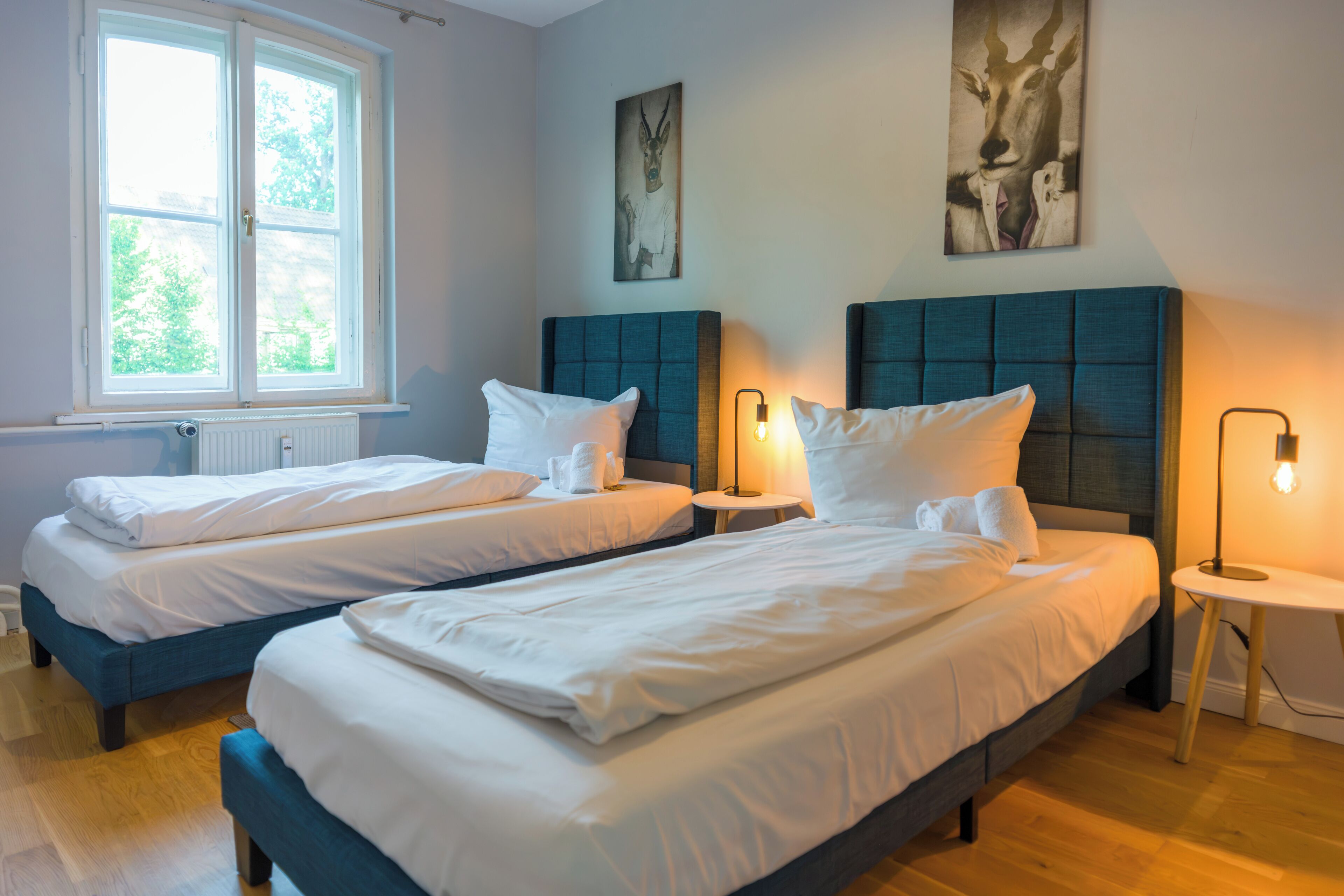 Ein Hotelzimmer mit zwei Betten, einem Fenster und Kunstwerken an den Wänden.