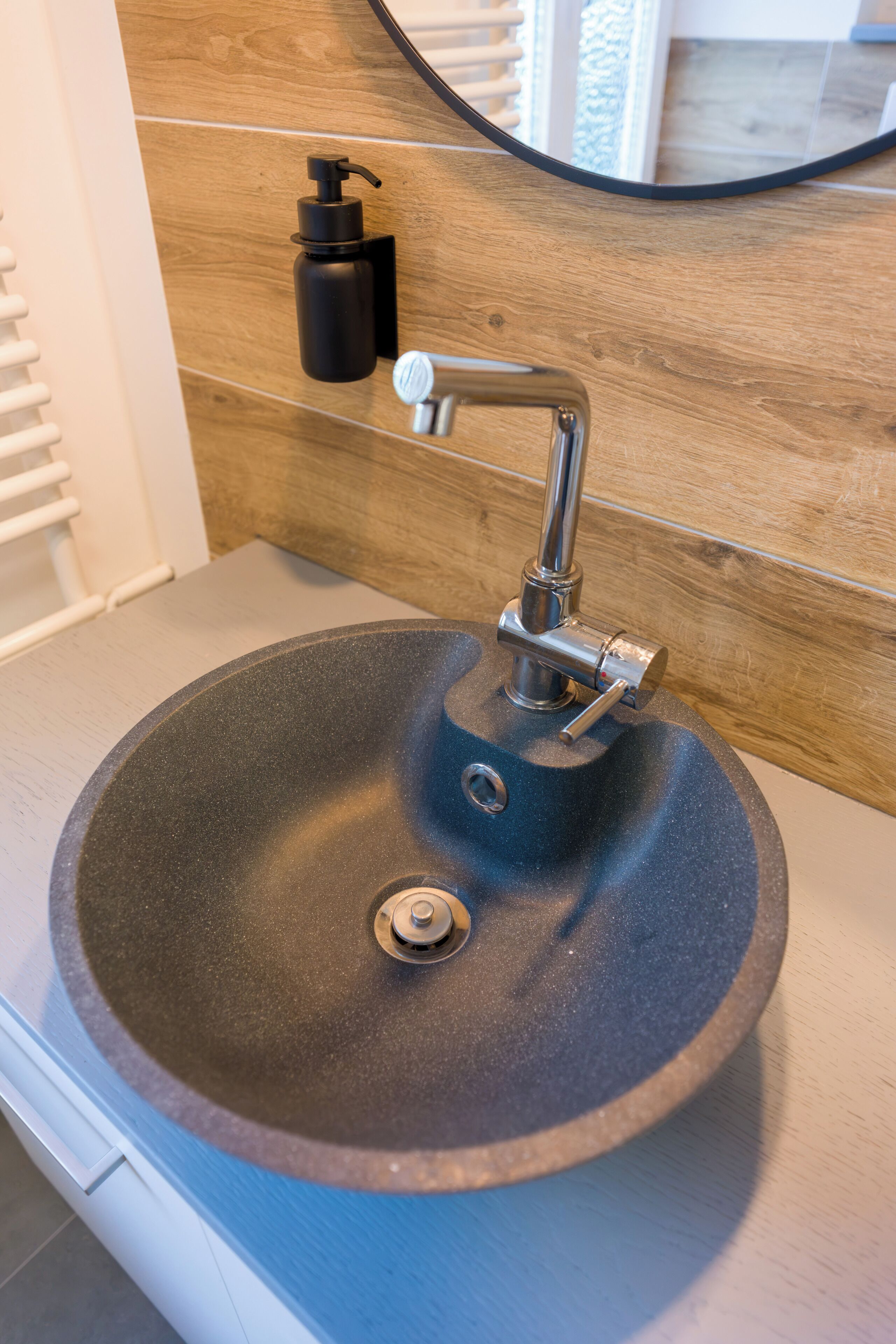 A bathroom sink with a modern faucet and a soap dispenser on the wall.