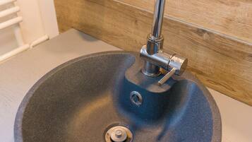 A bathroom sink with a modern faucet and a soap dispenser on the wall.