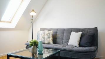 A modern living room with a grey sofa, a glass coffee table, and a floor lamp.