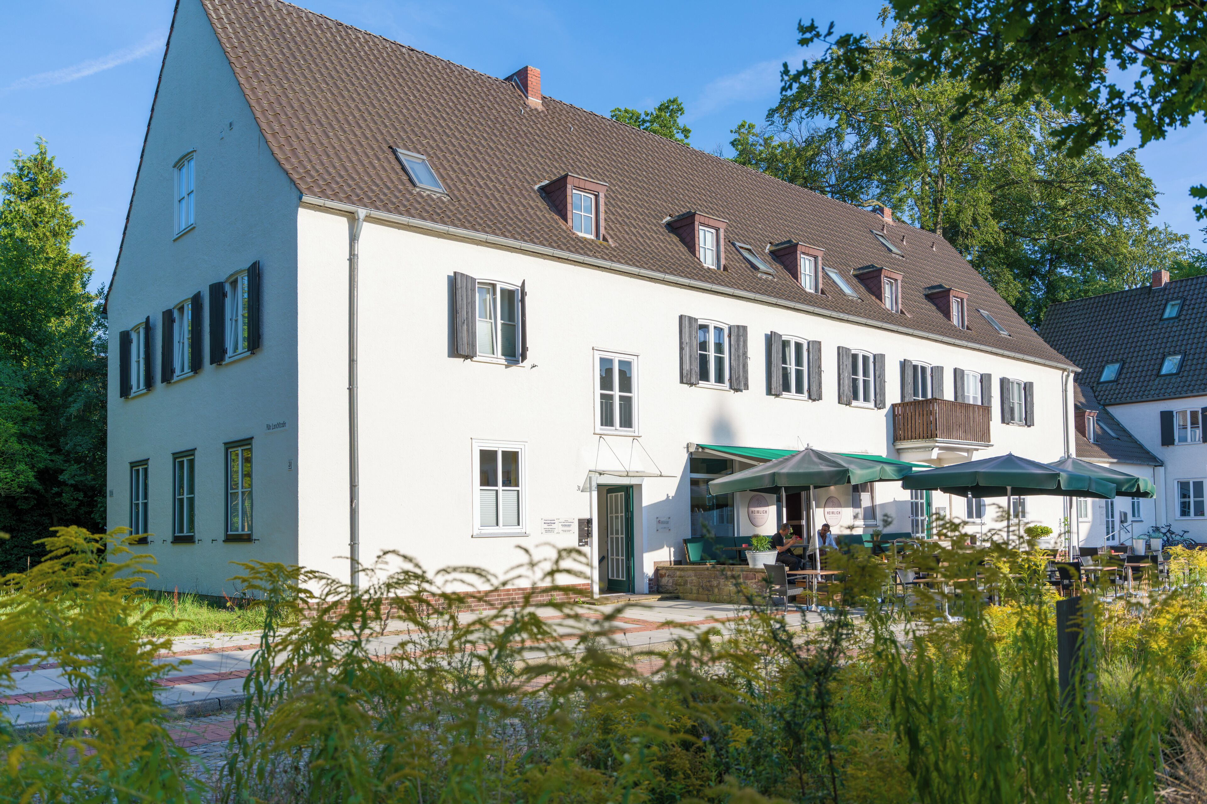Ein zweistöckiges Gebäude mit einem geneigten Dach, mehreren Fenstern mit Fensterläden und einem sichtbaren Eingang.