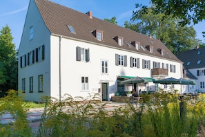 A two-story building with a sloped roof, multiple windows with shutters, and a visible entrance. - green-man Marktplatz Apartments (Wolfsburg)