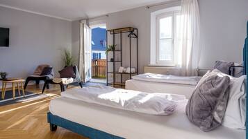 A bedroom with two beds, a chair, a small table, and a plant.