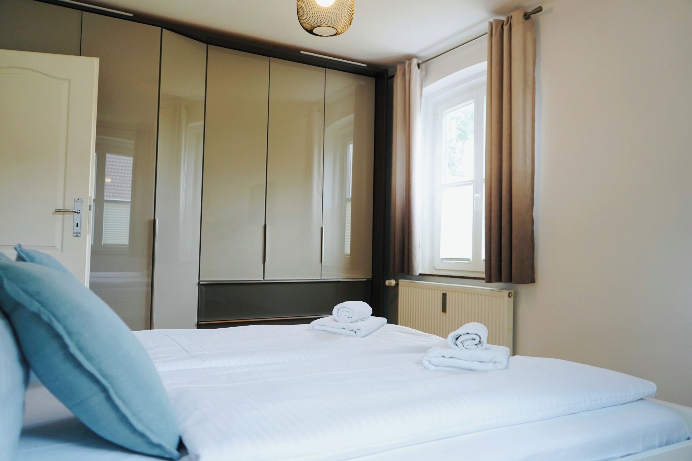 Ein Hotelzimmer mit Bett, Schrank, Heizkörper und einem fenster mit Vorhängen.