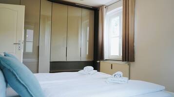 Ein Hotelzimmer mit Bett, Schrank, Heizkörper und einem fenster mit Vorhängen.