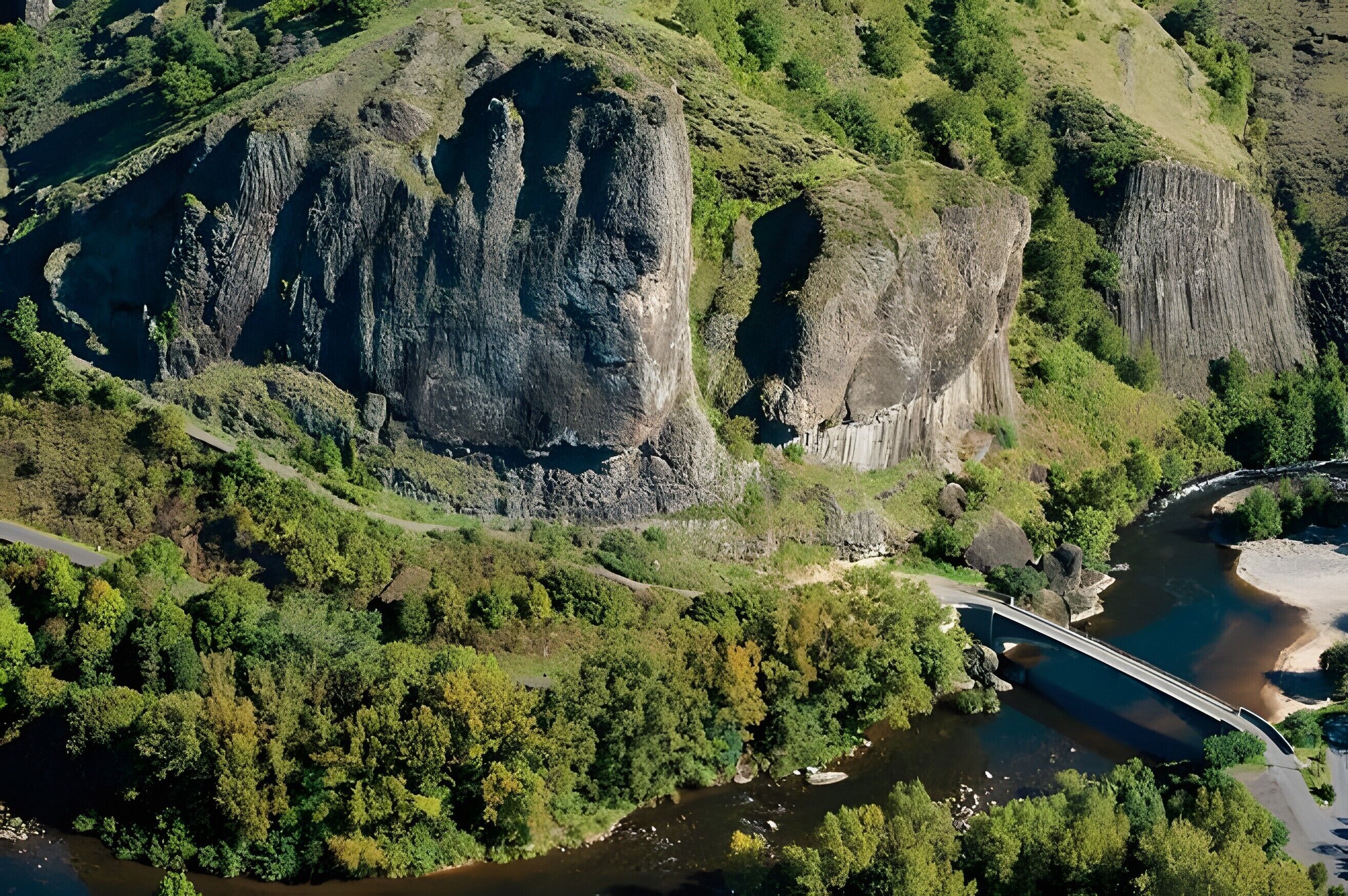 A mountainous landscape with a river, a bridge, and a road.