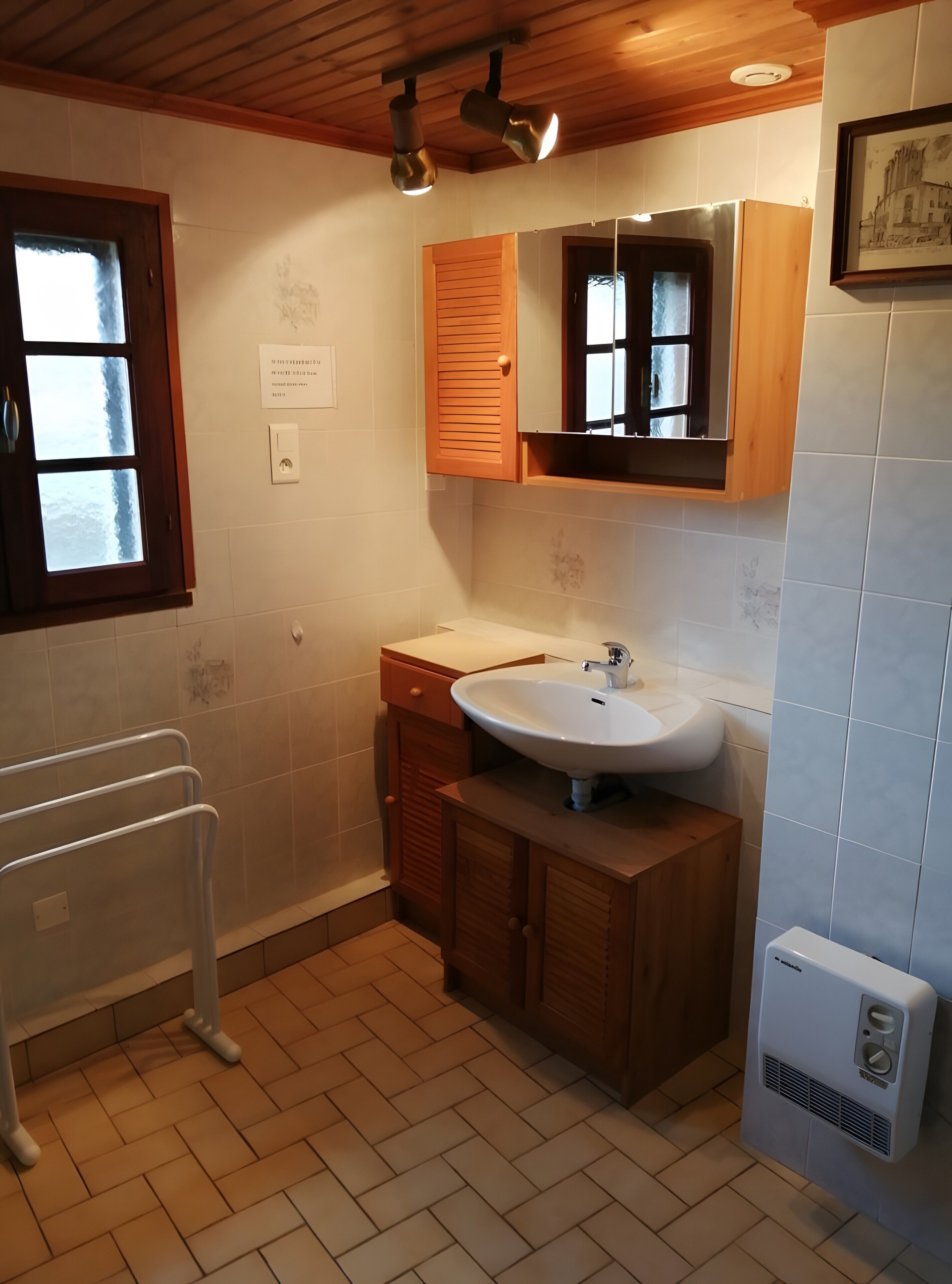 Une salle de bain avec un meuble-lavabo en bois, un lavabo blanc et une fenêtre à vitre dépolie.