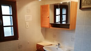 Kylpyhuoneessa on puinen allaskaappi, valkoinen allas ja ikkuna, jossa on himmeä lasi.
