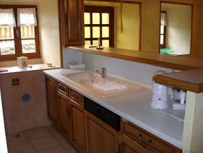 A kitchen with wooden cabinets, a double sink, and a coffee maker.