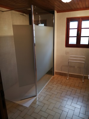 Une salle de bain avec une douche, une fenêtre et un porte-serviettes.