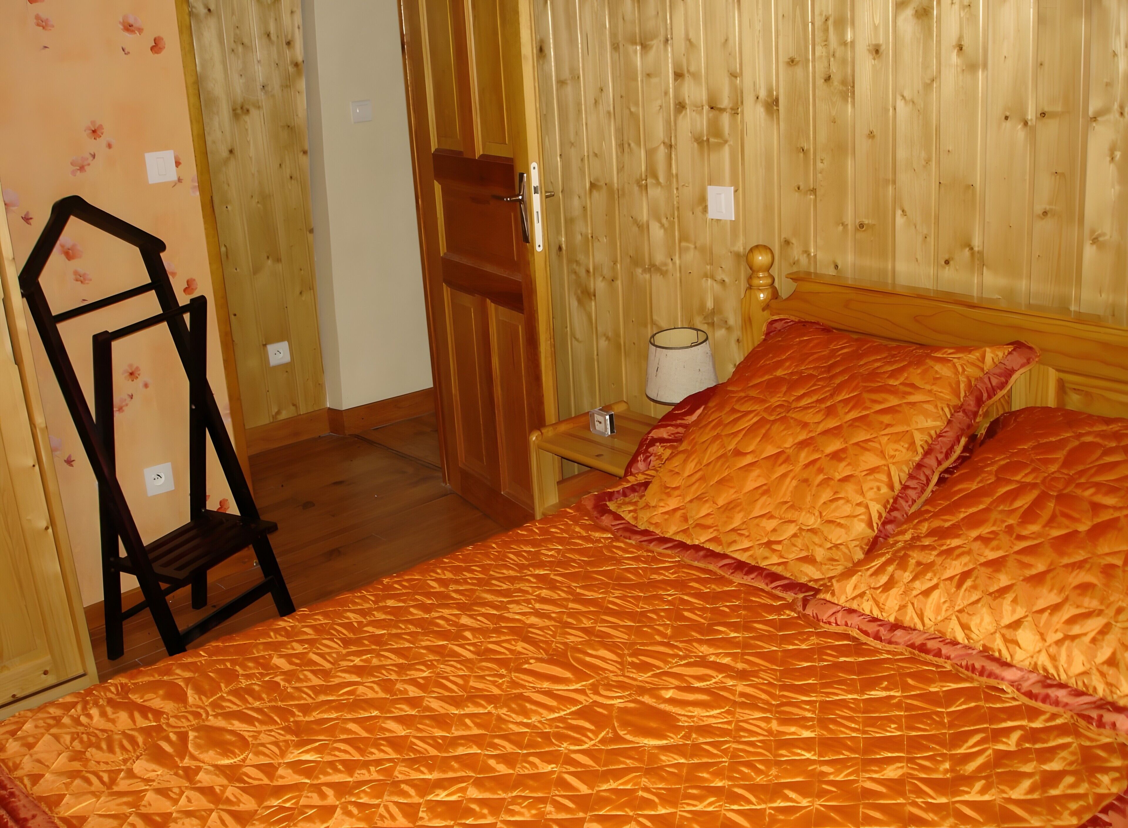 Une pièce avec un lit, des murs en bois, une table de chevet, une lampe et une chaise.