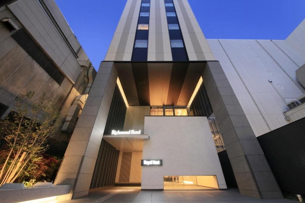 A modern hotel entrance with a flat facade, a sign for the Richmond Hotel, and a Royal Hotel sign below.