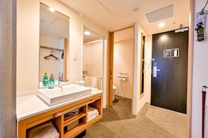 Casa de banho de hotel com um espelho grande, uma pia e um porta-toalhas.