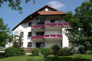 A multi-story residential building with balconies adorned with flowers, surrounded by greenery. - House at Gutach No. 12 (Titisee-Neustadt)