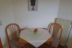 A small dining area with a table covered by a white tablecloth, two wooden chairs, and a small decorative item on the table. - House at Gutach No. 12 (Titisee-Neustadt)
