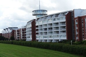 A modern multi-story residential building with balconies and a central tower. - Holiday apartment with 1 bedroom (Wilhelmshaven)