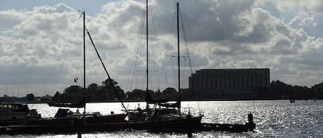 A marina with boats docked, a building in the background, and a cloudy sky.