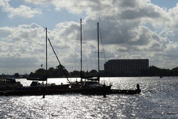 En småbåtshamn med förtöjda båtar, en byggnad i bakgrunden och en molnig himmel.