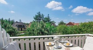 A balcony with a table set for tea, overlooking a residential area with houses and trees. - Ordinger Dün Holiday Apartment 6 (St. Peter-Ording)