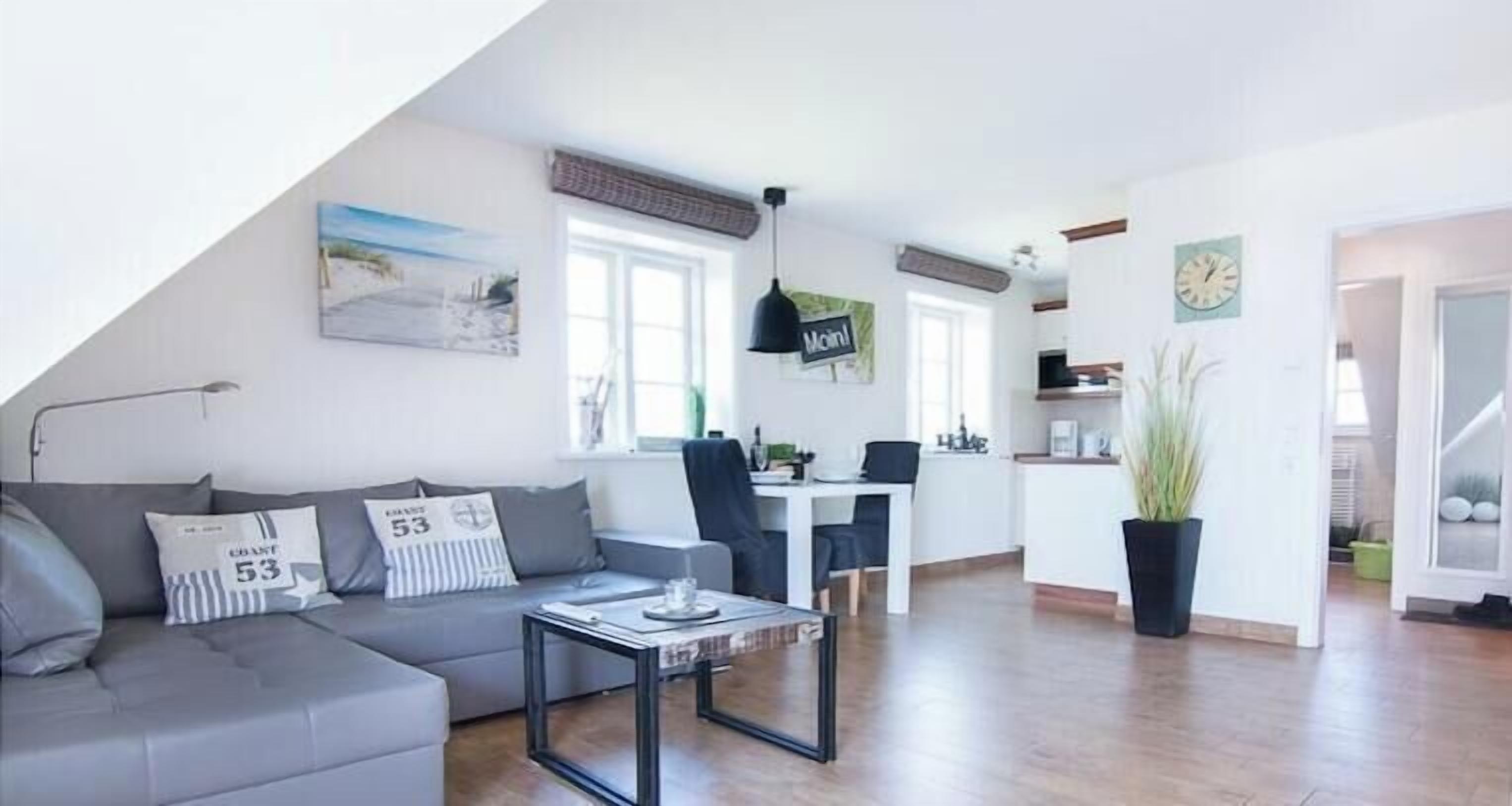 Una sala de estar moderna con un sofá gris, una mesa de centro y una zona de comedor con una silla y una mesa.