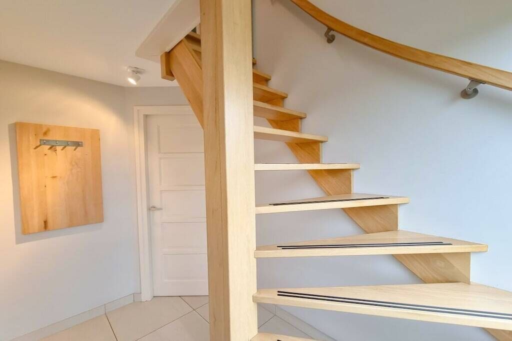 Een houten trap met een leuning en een deur onderaan.