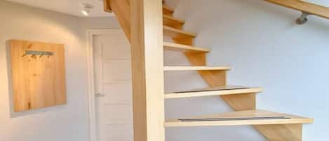 Una escalera de madera con barandilla y una puerta al final.