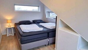 Une chambre à coucher de taille modeste, comprenant un lit, des tables de chevet et une fenêtre.