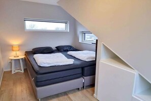 Een kleine slaapkamer met een bed, nachtkastjes en een raam.