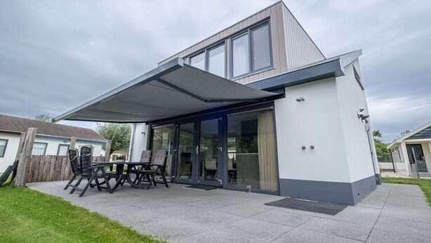 Une maison moderne dotée d’un patio couvert, de grandes fenêtres et d’un toit plat.