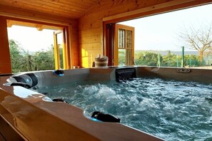 Een hottub in een houten blokhut met uitzicht op de natuur.