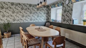 Ruokailutila, jossa on pyöreä pöytä, tuoleja, ruukkukasvi ja seinä, jossa on lehtikuvio.