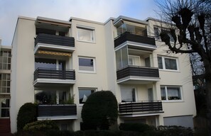 Ein mehrgeschossiges Wohngebäude mit Balkonen, Fenstern und einer glatten Fassade.