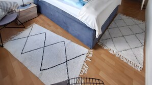Un dormitorio moderno con cama, mesitas de noche, una silla y un espejo grande.