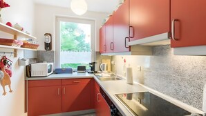 Una cocina compacta con armarios rojos, microondas, tostadora y estufa.
