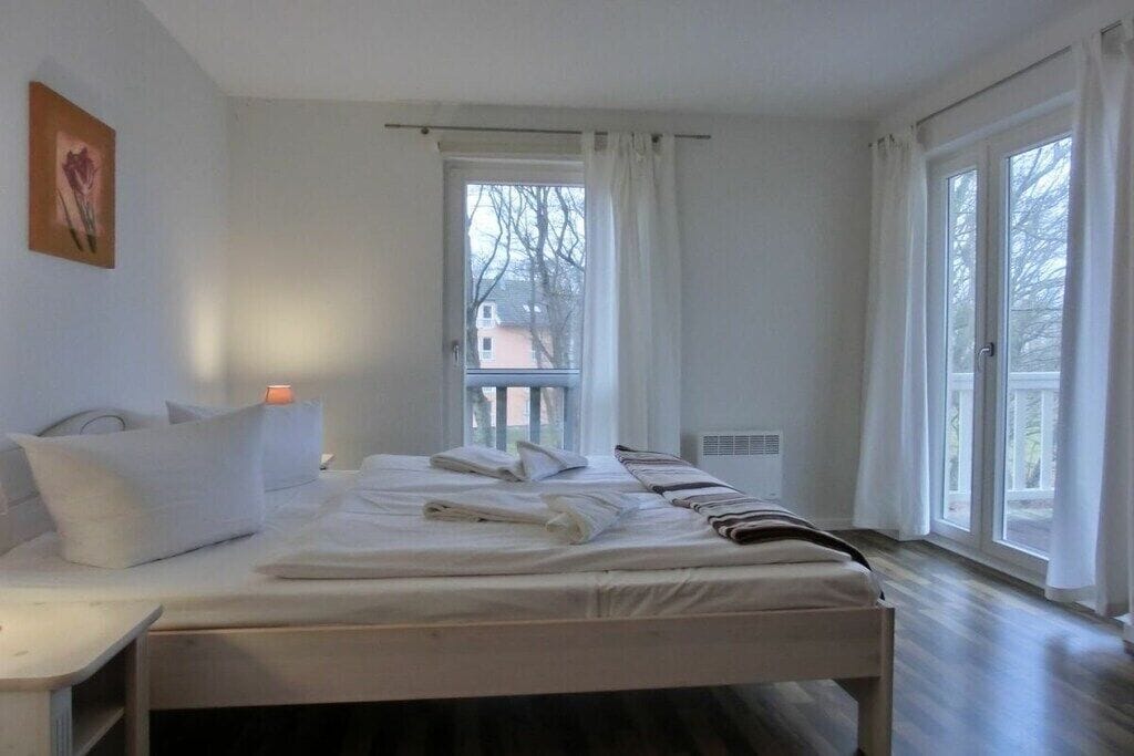 A bedroom with a bed, a bedside table, a window, and a view of the outside.