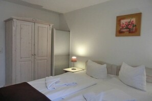 Ein Hotelzimmer mit Bett, Schrank, Nachttisch mit Lampe und einem Bild an der Wand.