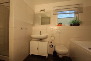 Een badkamer met een witte wastafel, een toilet en een douche.