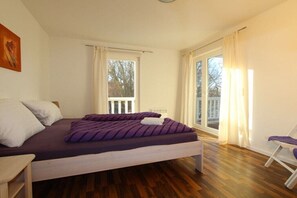 Een slaapkamer met een bed, een stoel en een raam.