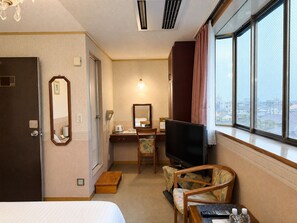 A hotel room with a bed, a desk with a chair, a television, and a large window with curtains. - WASHUKAN HOTEL  (Gyoda)
