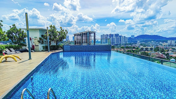 A rooftop infinity pool with a city view, wooden deck, and lounge chairs. - Cozy Suites at Saville Cheras by HCK (Cheras)