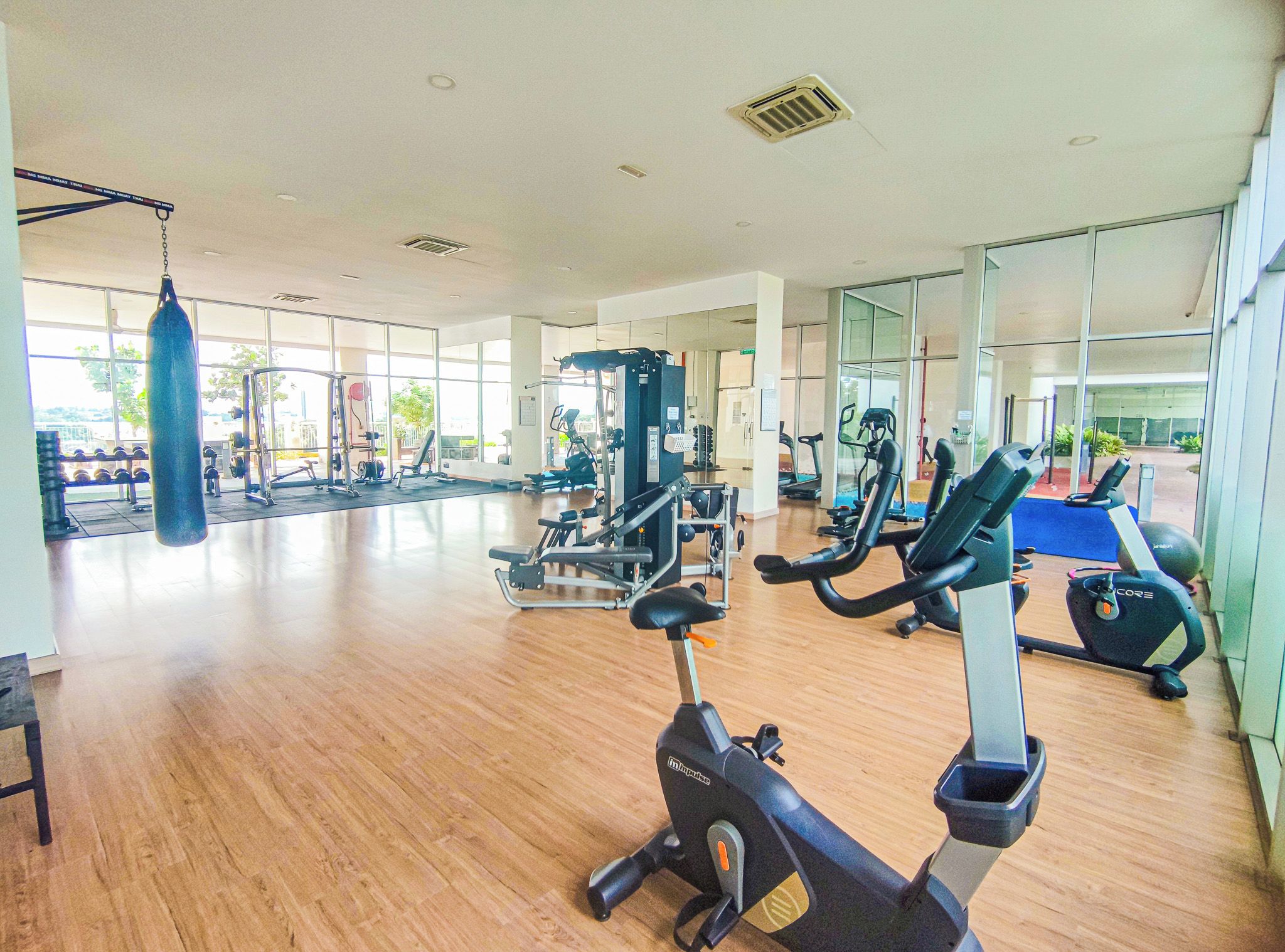 Un gimnasio con máquinas de cardio, equipo de levantamiento de pesas y un saco de boxeo.