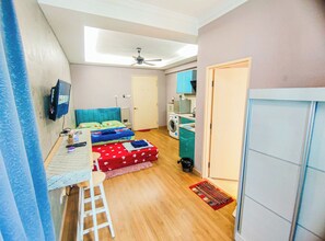 Habitación pequeña con cama, escritorio, lavadora y ventilador de techo.