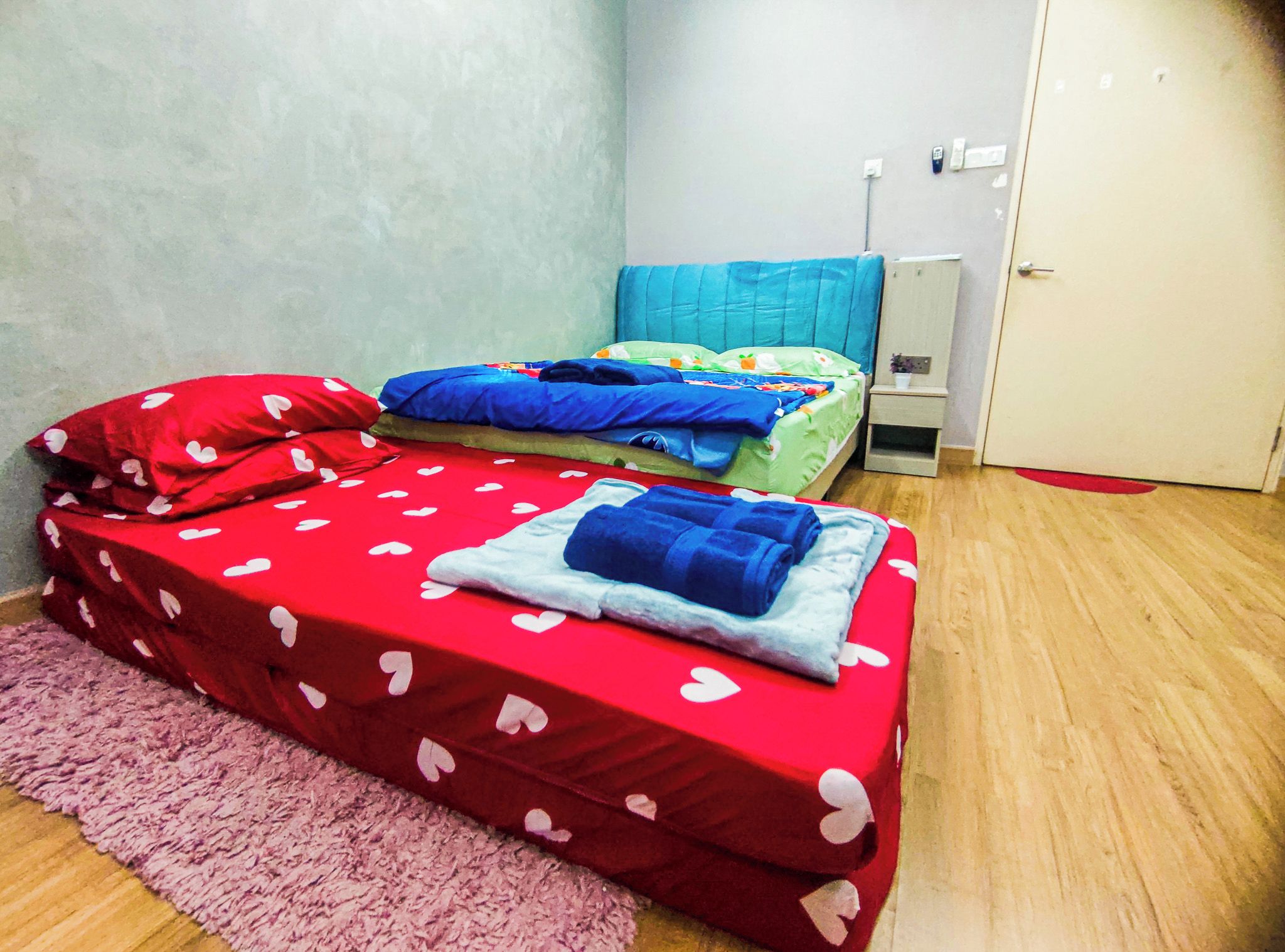 Un alojamiento pequeño de una sola habitación con dos camas, una alfombra rosa y una puerta.