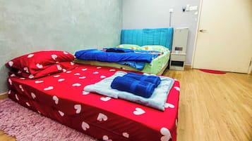 Un alojamiento pequeño de una sola habitación con dos camas, una alfombra rosa y una puerta.