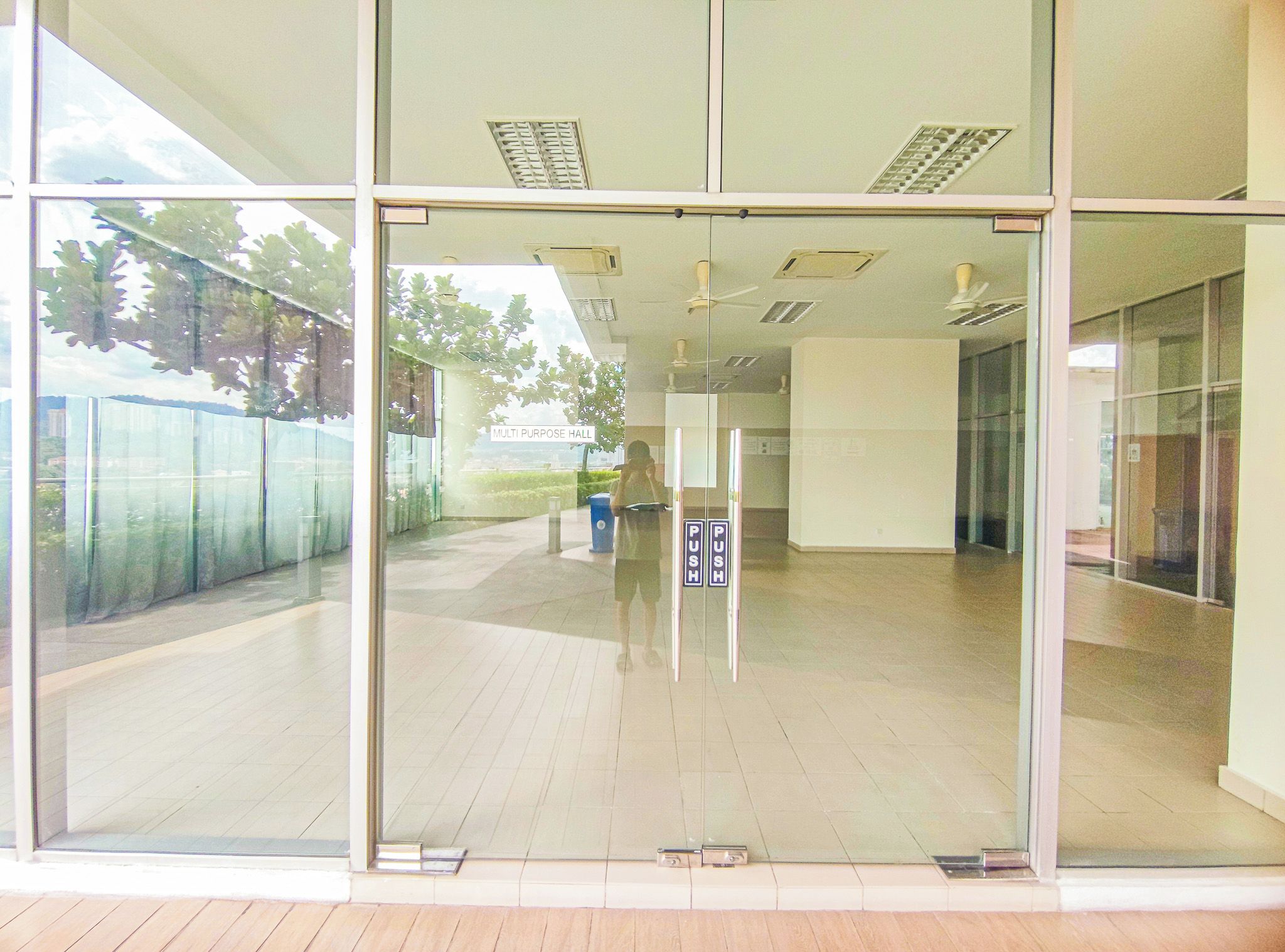 A multi-purpose hall with glass doors, ceiling fans, and a sign indicating a push bar.