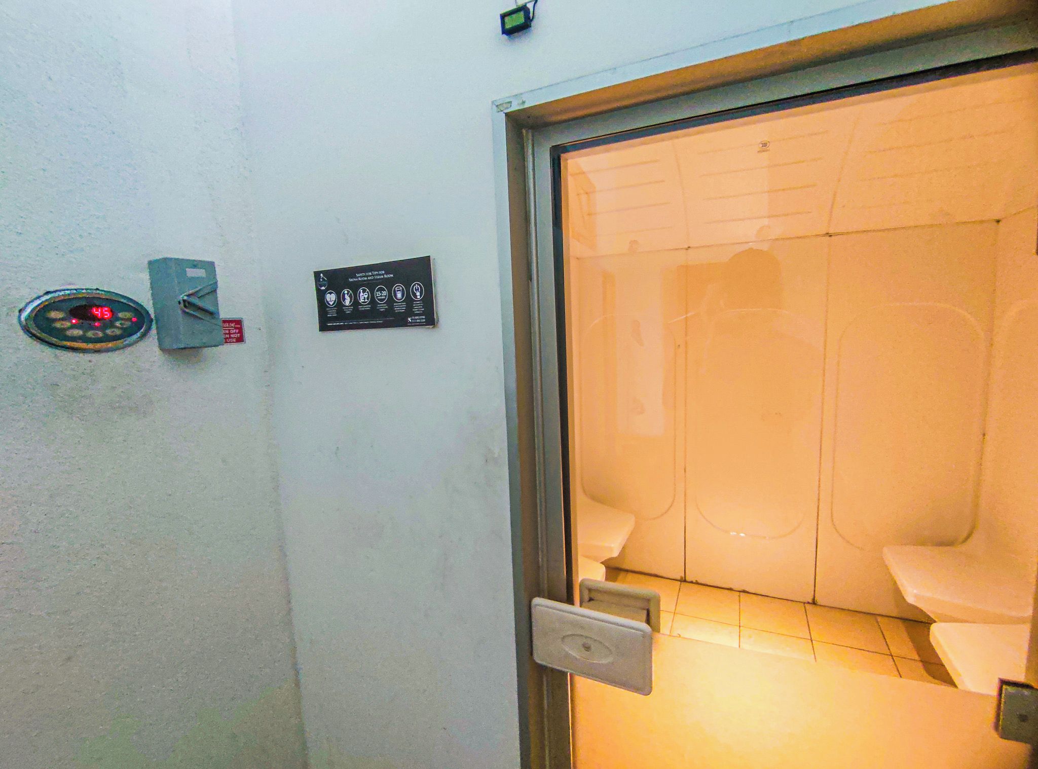 Toilet med håndtørrer og et skilt på væggen med sikkerhedsanvisninger.