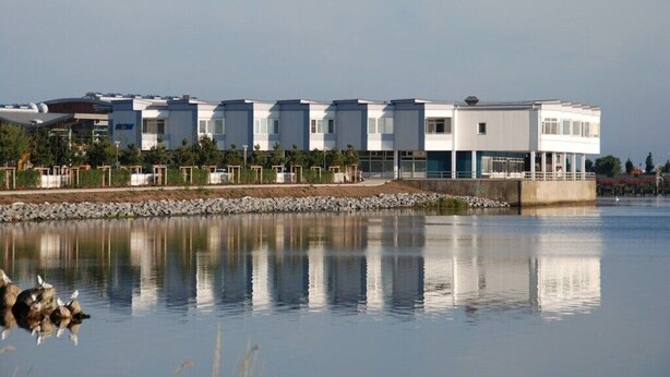 Un bâtiment moderne avec une étendue d’eau réfléchissante devant, probablement un hôtel ou un complexe touristique.